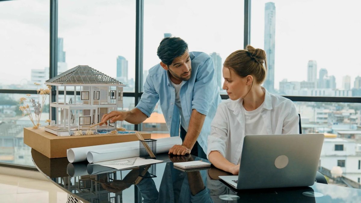 smart-engineer-inspect-house-model-while-colleague-using-laptop-tracery