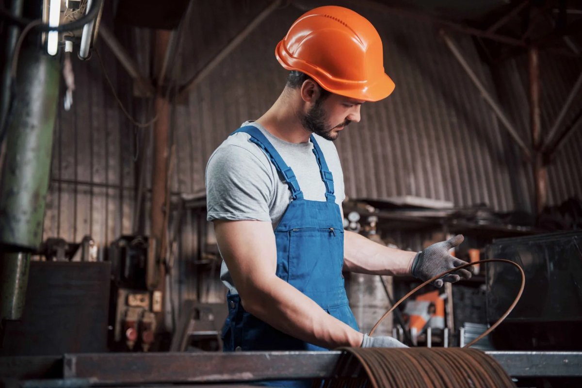 Worker handling metal wire in factory